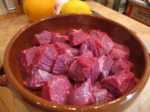 500 g høyrygg av okse skjæres i terninger på størrelse med fyrstikkeske. Hell en halv flaske rødvin over. Trenger ikke være noe fancy, men velg gjerne en Rhone-vin, for den er uansett god å drikke til retten.
