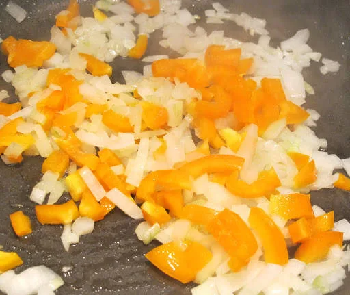 Mykne løk og paprika i en panne.