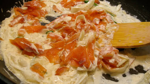 Tilsett fløteblandingen og rør den sammen med løk-miksen. Så har du forsiktig i røkelaksen og rører lett. Tilsett et par teskjeer med sitronsaft i retten.