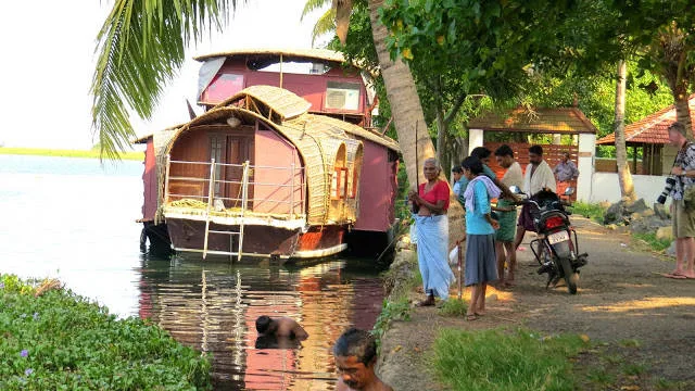 Vår kanalbåt til kai. Mannen i front vasker seg i det passe skitne vannet, mens mannen i midten fanger fisk med bare hendene.