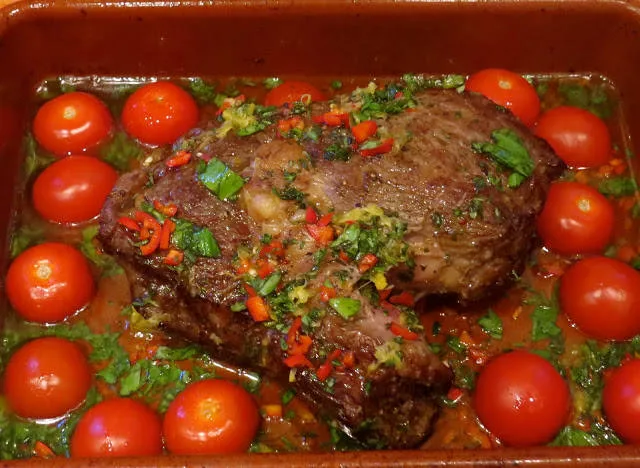 Ta ut formen fra ovnen: Når kjøttet er stekt ferdig (jeg liker det rødt i midten), lar du det ligge i den ildfaste formen og drysser over en god olivenolje (6-7 ss) og alle de deilige urtene. Snu kjøttet og sørg for at urtene og sitronskallet dekker flatene på kjøttet. Formen er nå varm fra ovnen og er du lur, legger du en drøss med halve cherrytomater i formen og lar de få suge opp de deilige saftene fra oljen og kjøttet. Legg med snittsiden ned. Damp noen grønne bønner og lag noen deilige frityrstekte (evt pannestekte) potetbåter.