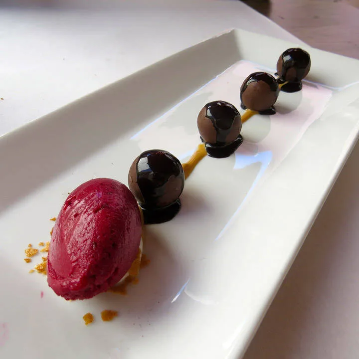 Sjokoladekuler med flytende sjokoladefyll servert med solbærsorbet og hasselnøttkrem. En eksplosjon i munnen.