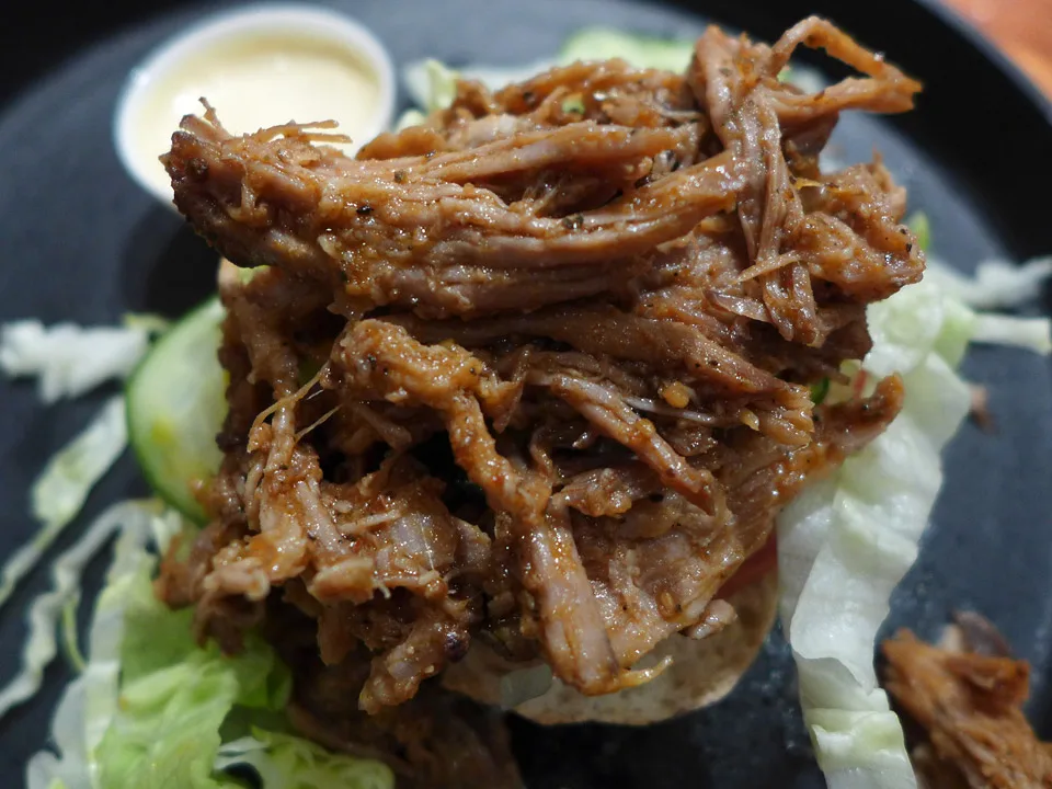Server pulled pork på strimlet salat og med tomatskive.