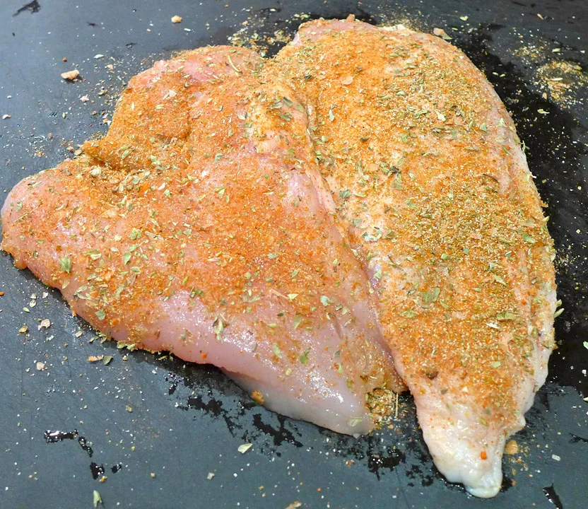 Krydre et kvalitetskyllingbryst med krydder på begge sidene.