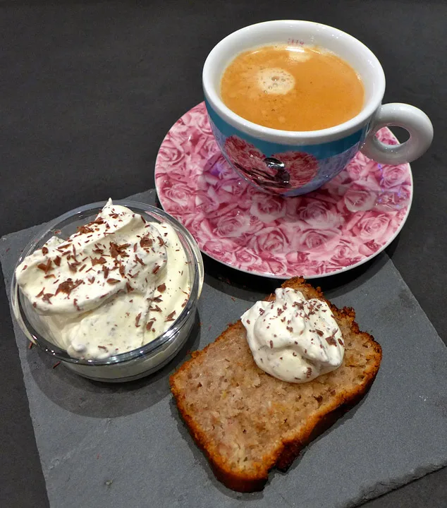 Kaffe, eplekake og krem med revet sjokolade.