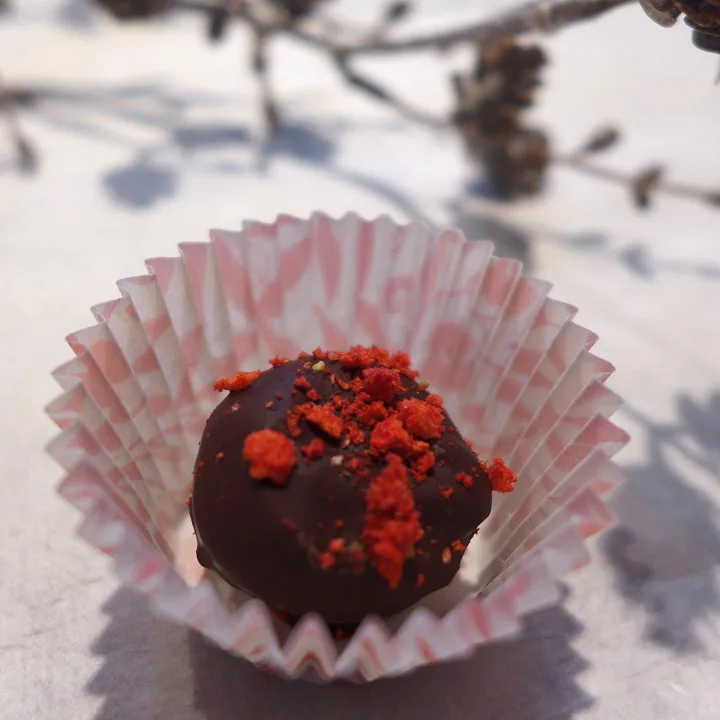 Trøflene er blandet med krokan (ristede nøtter og karamell som er hakket grovt). Mørkt sjokoladetrekk og pulverisert jordbær på toppen. 