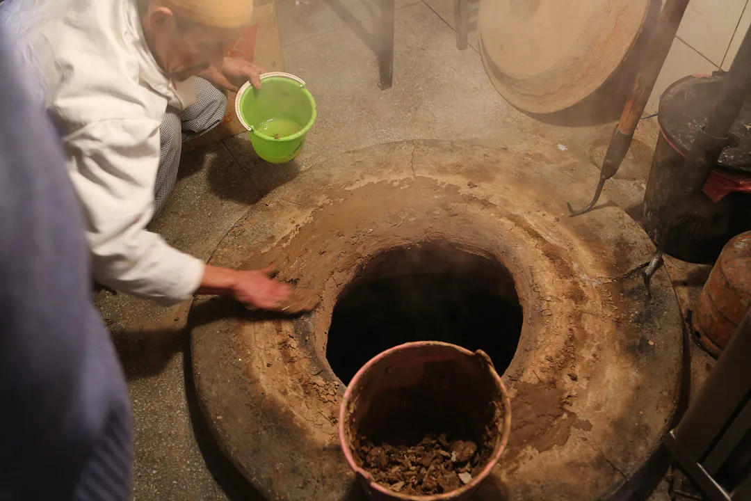 Krukkene senkes ned i hull i bakken der det fyres med ved.