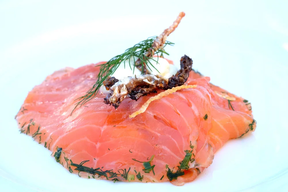 Restaurant Kronborgs lekre laksesmørrebrød på lyst brød.Gravet laks med urter og lime og fritert lakseskinn.